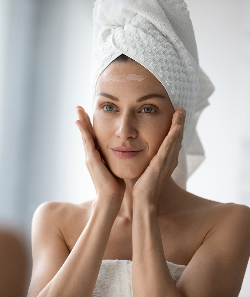 Woman with a towel on her head touching her face